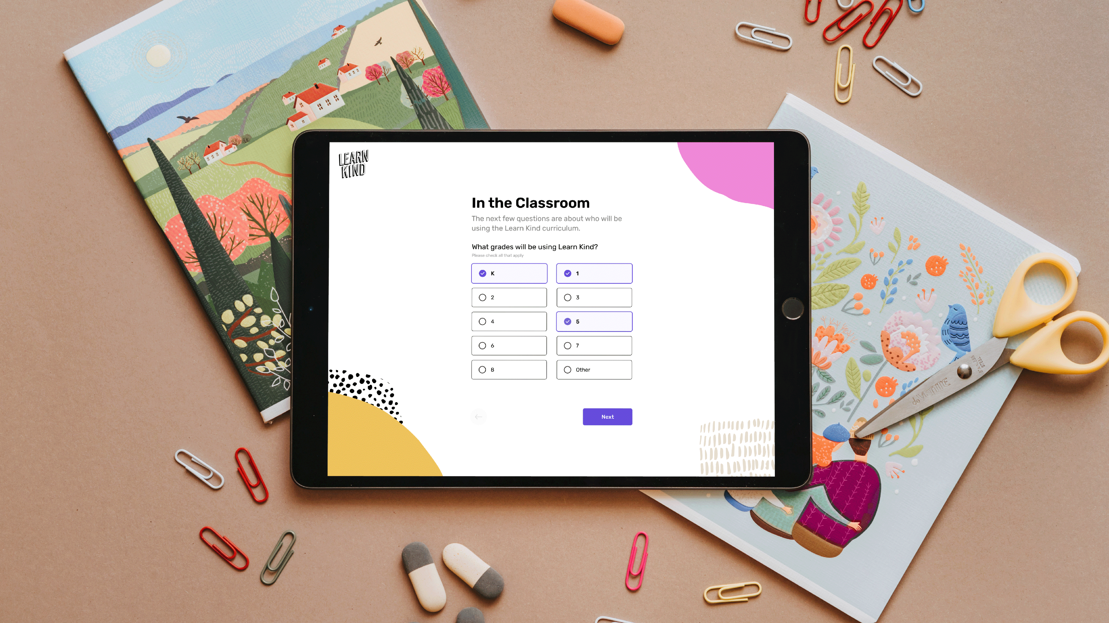 Tablet displaying classroom settings survey, surrounded by art supplies and colorful books.